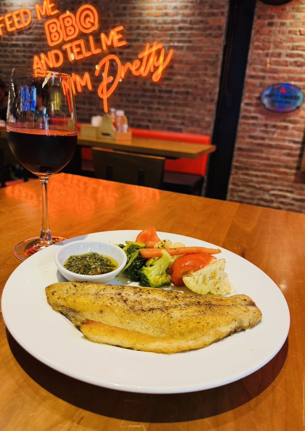 Fish with vegetables, sauce and a glass of red wine.